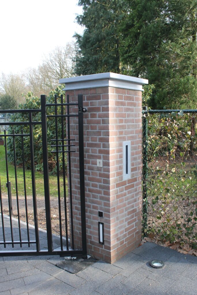 Gemetselde kolom met natuurstenen pet met chique rand. In de kolom is de natuurstenen brievenbusgleuf ingemetseld. Maatwerk Verlaichting in de gemetselde kolom en een ingebouwde fotocel t.b.v. de veiligheid van de automatische poort.