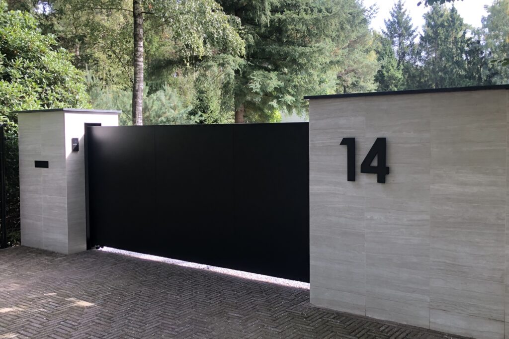 Automatische schuifpoort met natuurstenen kolommen. Dichte strakke schuifpoort . De poort sluit in de muur wat een chique geheel vormt.