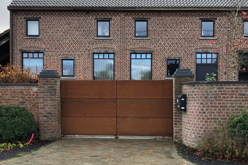 Cortenstaal dichte draaipoort tussen 2 gemetselde pilasters.