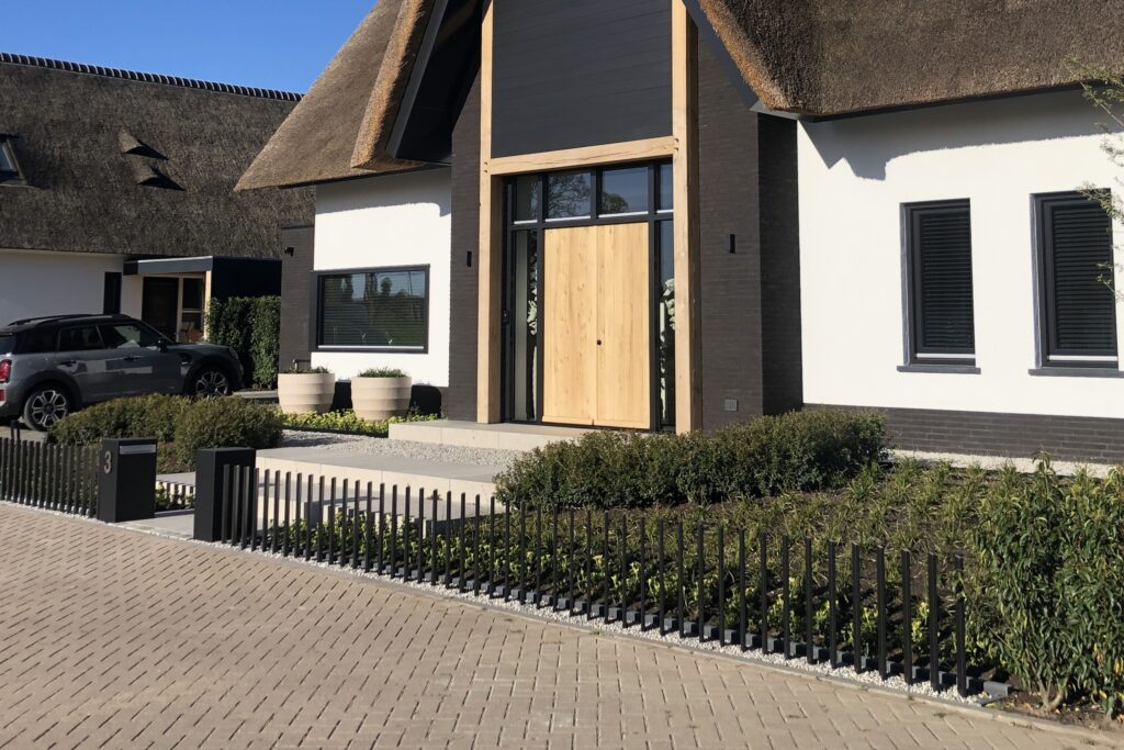 Laag hekwerk van lamellen. Passend bij een moderne woning.